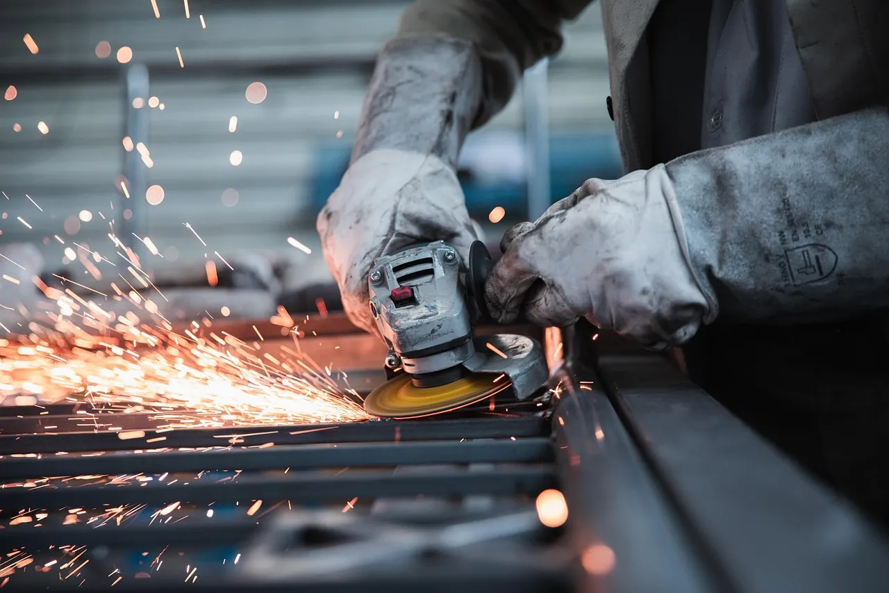Fabricator deburring steel with an angle grinder in a metal shop