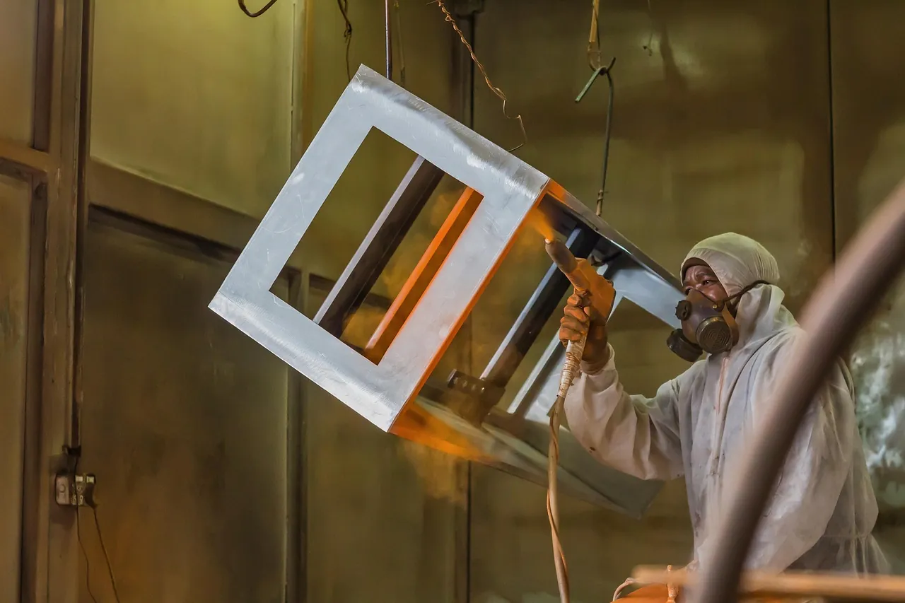 Technician powder coating a fabricated metal frame