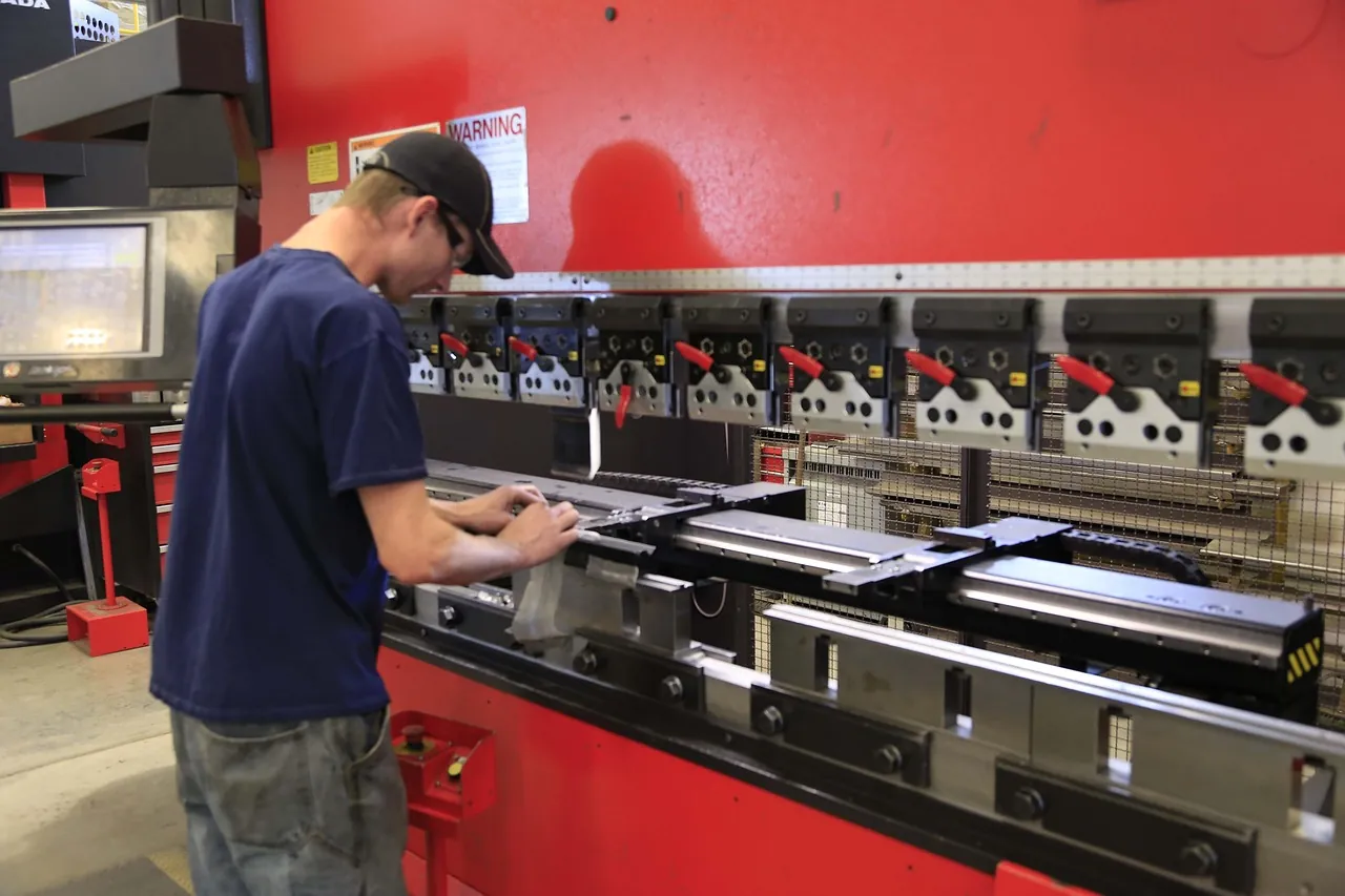 Operator setting up a sheet metal part at a press brake